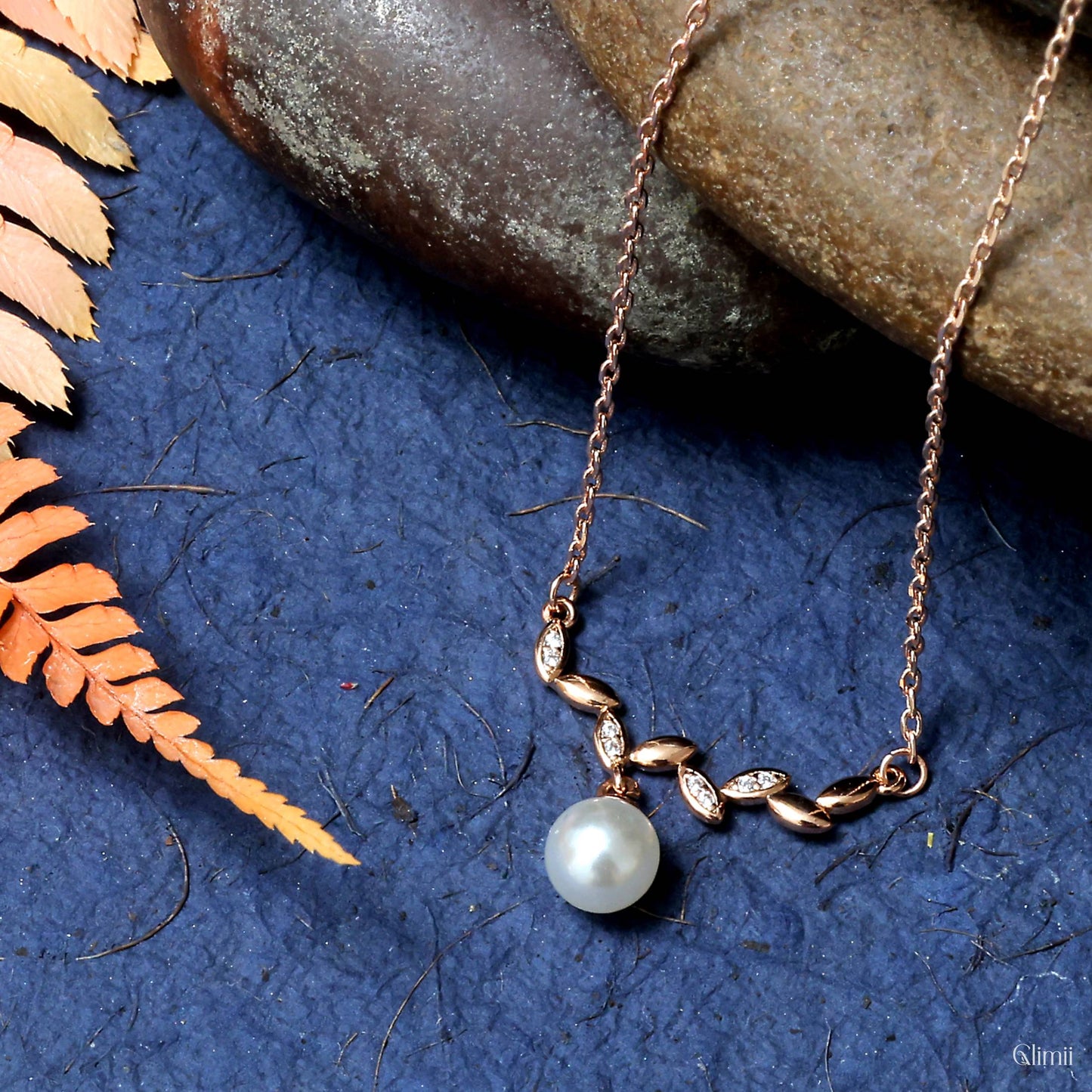 Glimii delicate stainless steel necklace with pearl and leaf design on blue textured background