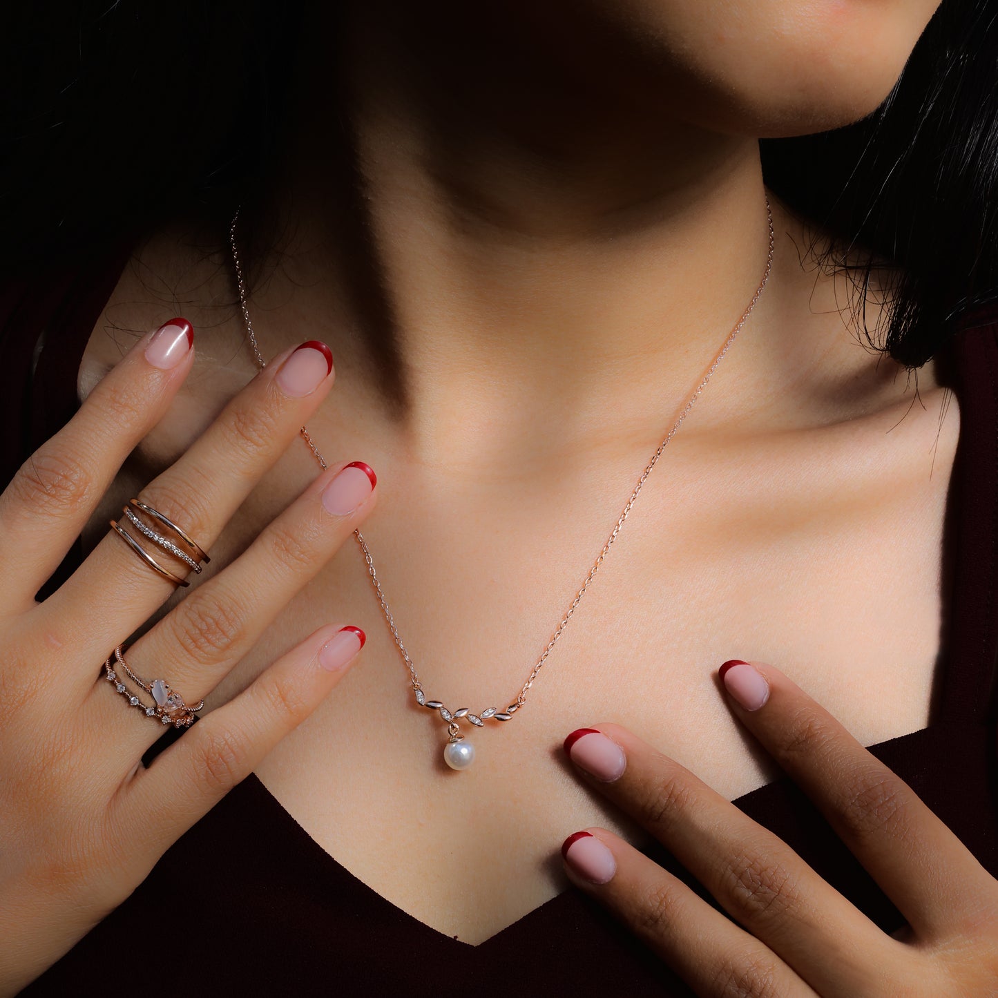 Glimii delicate stainless steel necklace with pearl pendant worn on neck with hands showing rings