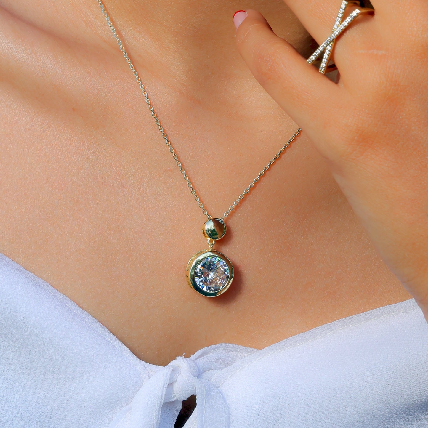 Glimii elegant layering necklace with a round crystal pendant worn with white top and diamond ring