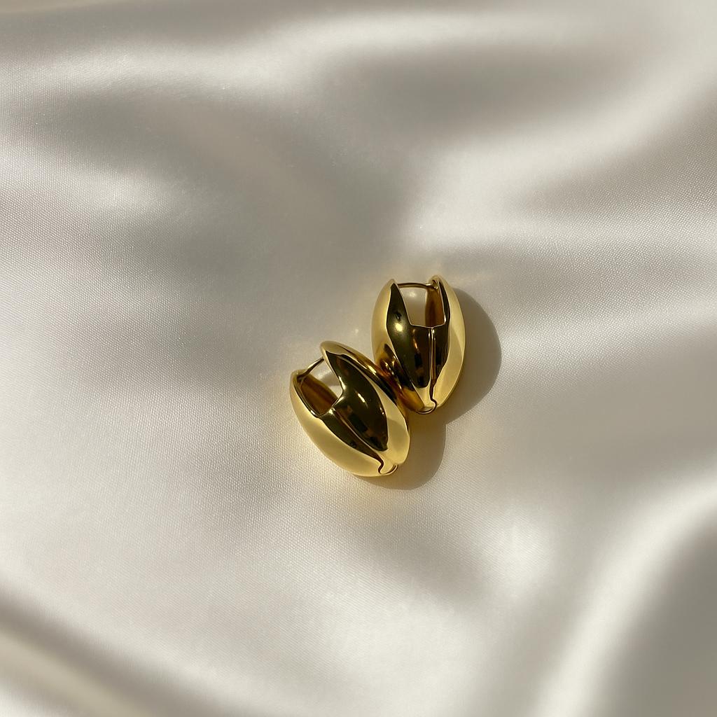 Glimii gold almond hoop earrings with smooth polished finish on white satin background