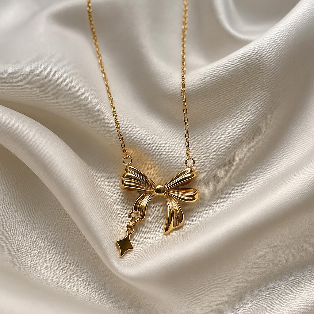 Glimii elegant gold bow necklace with delicate chain displayed on smooth silk fabric