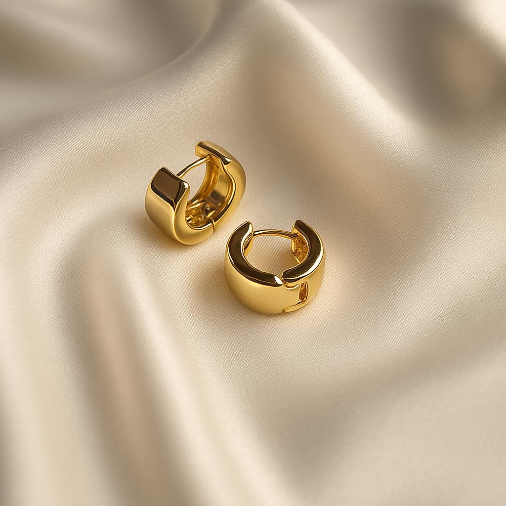 Glimii gold chunky hoop earrings with a polished finish displayed on smooth satin fabric