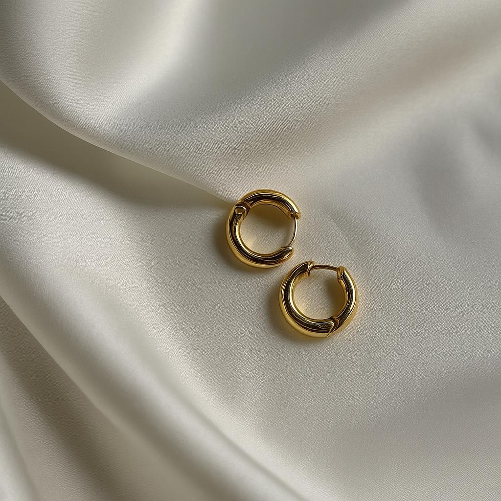 Glimii gold circle hoop earrings with smooth finish displayed on soft beige fabric background