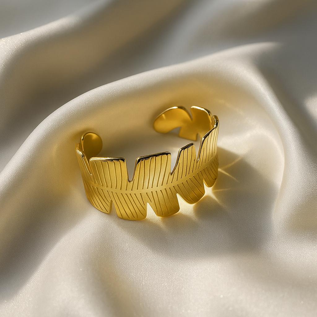 Glimii gold tone Korean style jewelry cuff with leaf design on smooth fabric background
