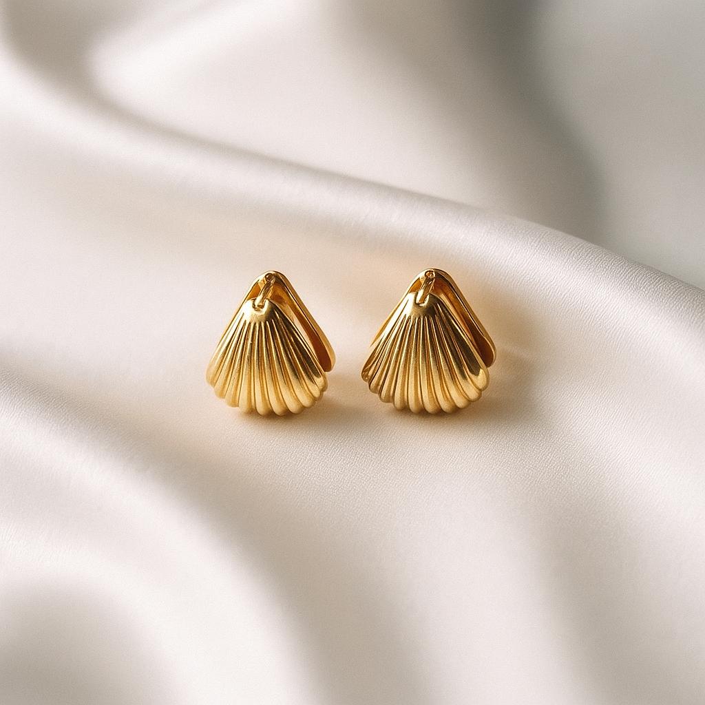 Glimii minimalist shell earrings for women in gold placed on soft white fabric background