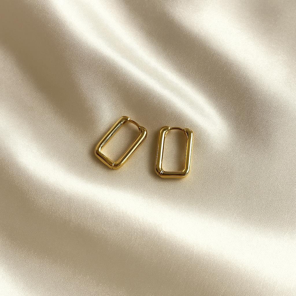 Glimii gold rectangular hoop earrings displayed on smooth cream satin fabric