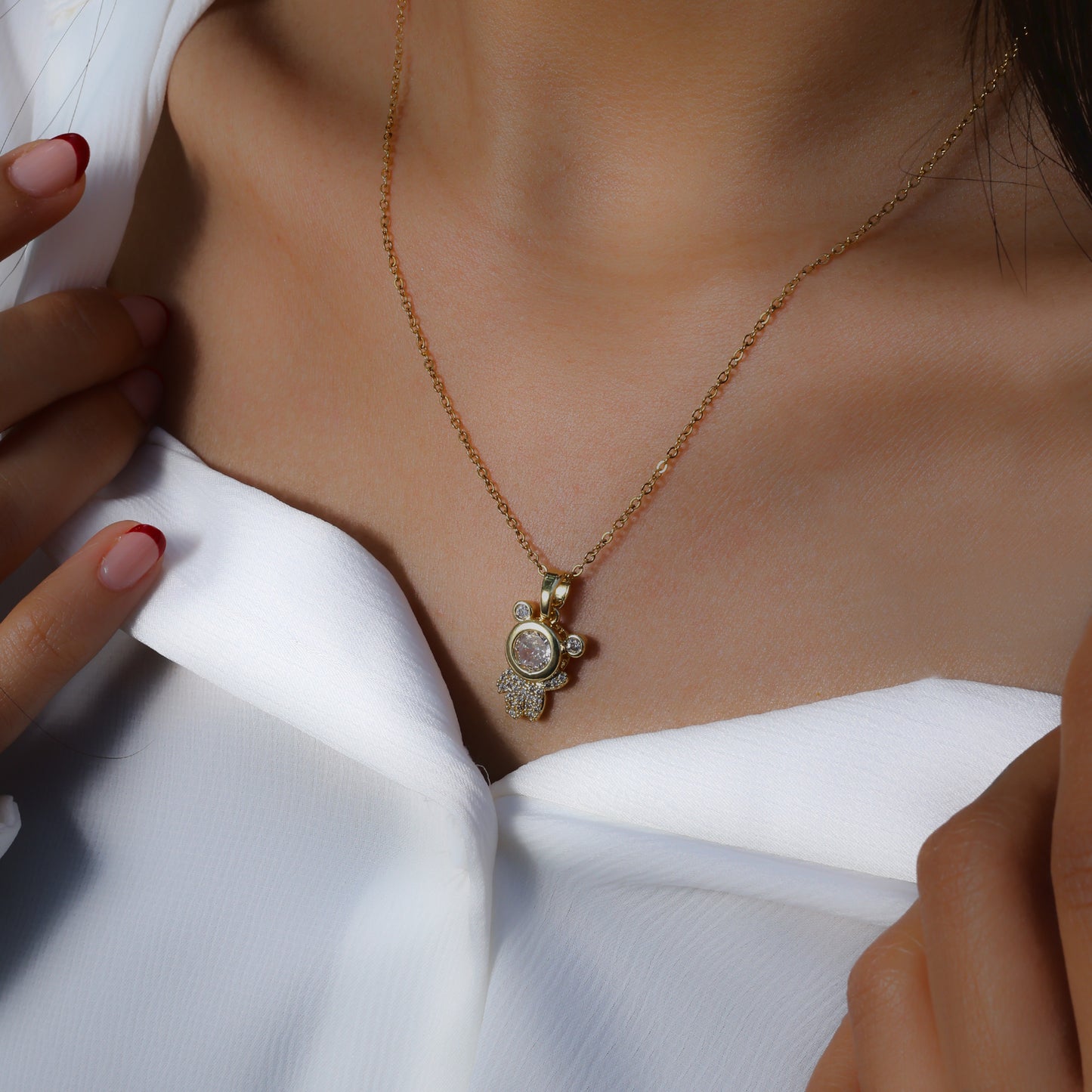 Glimii stainless steel astronaut charm necklace with gold chain worn on model in white top