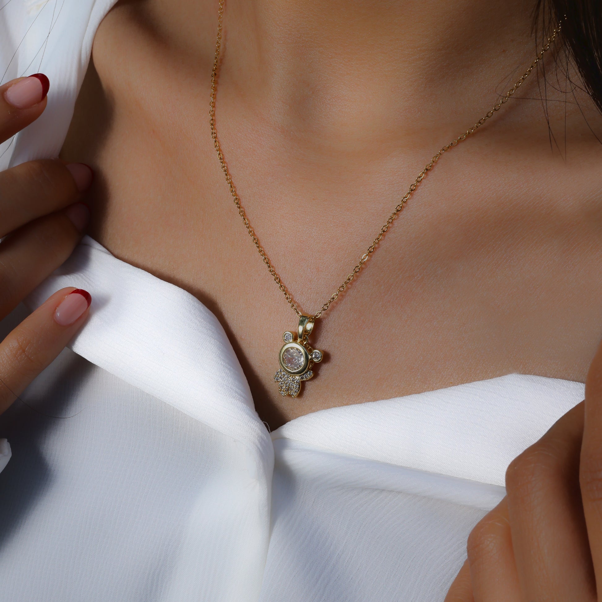 Glimii stainless steel astronaut charm necklace with gold chain worn on model in white top