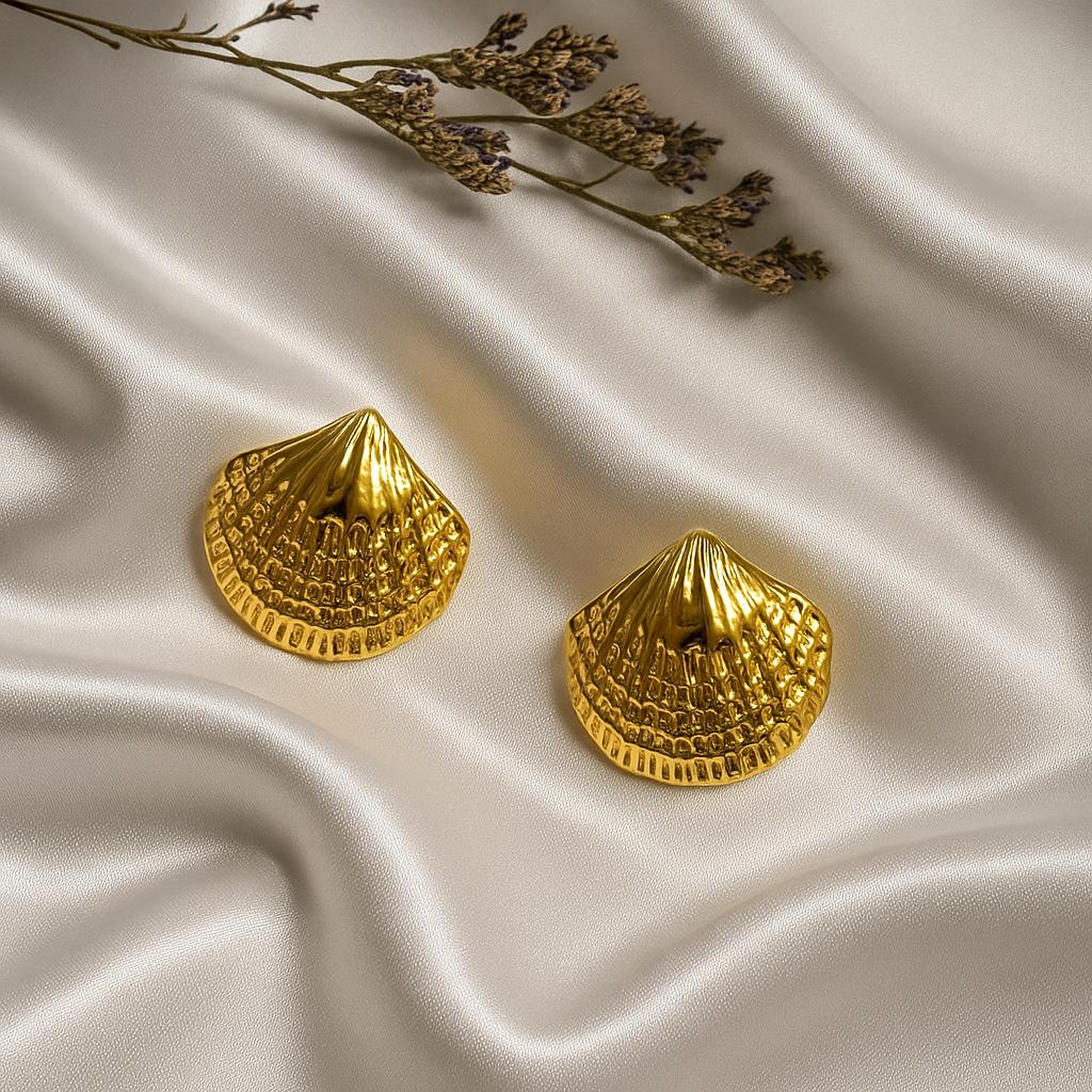 Glimii gold stainless steel shell earrings displayed on smooth satin fabric with dried flowers