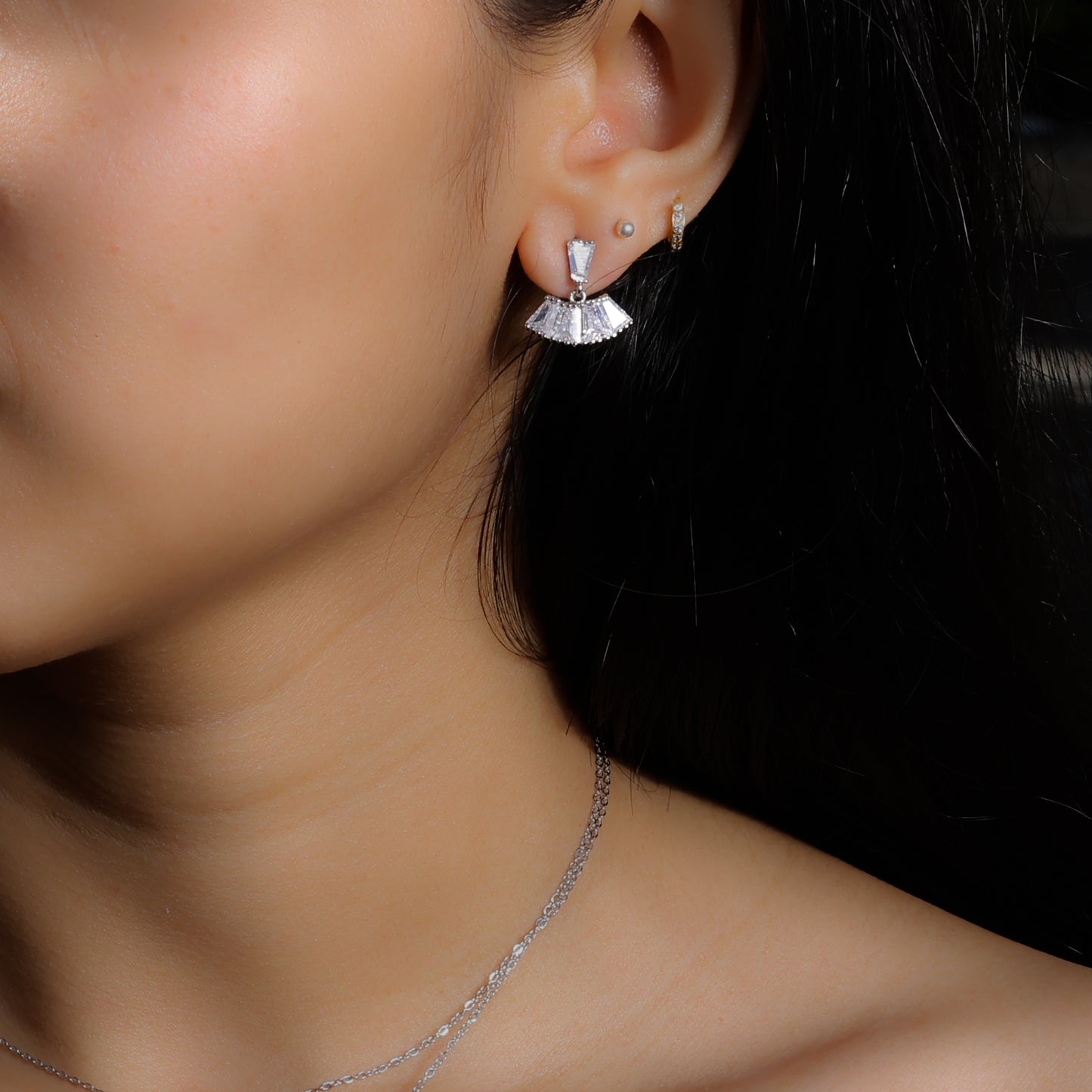 Glimii minimalist stainless steel earrings with fan-shaped design worn on ear with additional small hoop and stud earrings