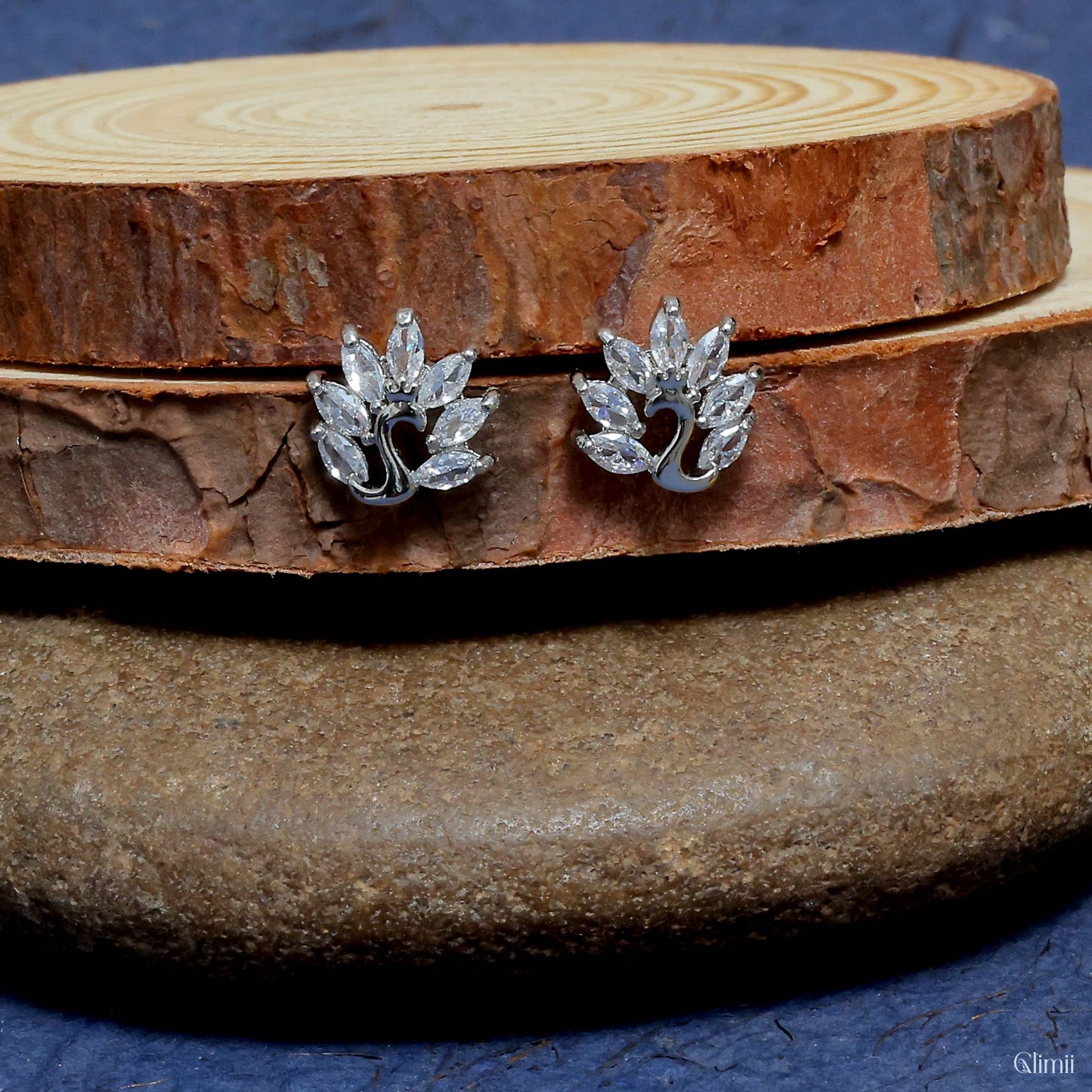 Glimii Korean style stud earrings with silver and clear crystal leaf design on wooden display