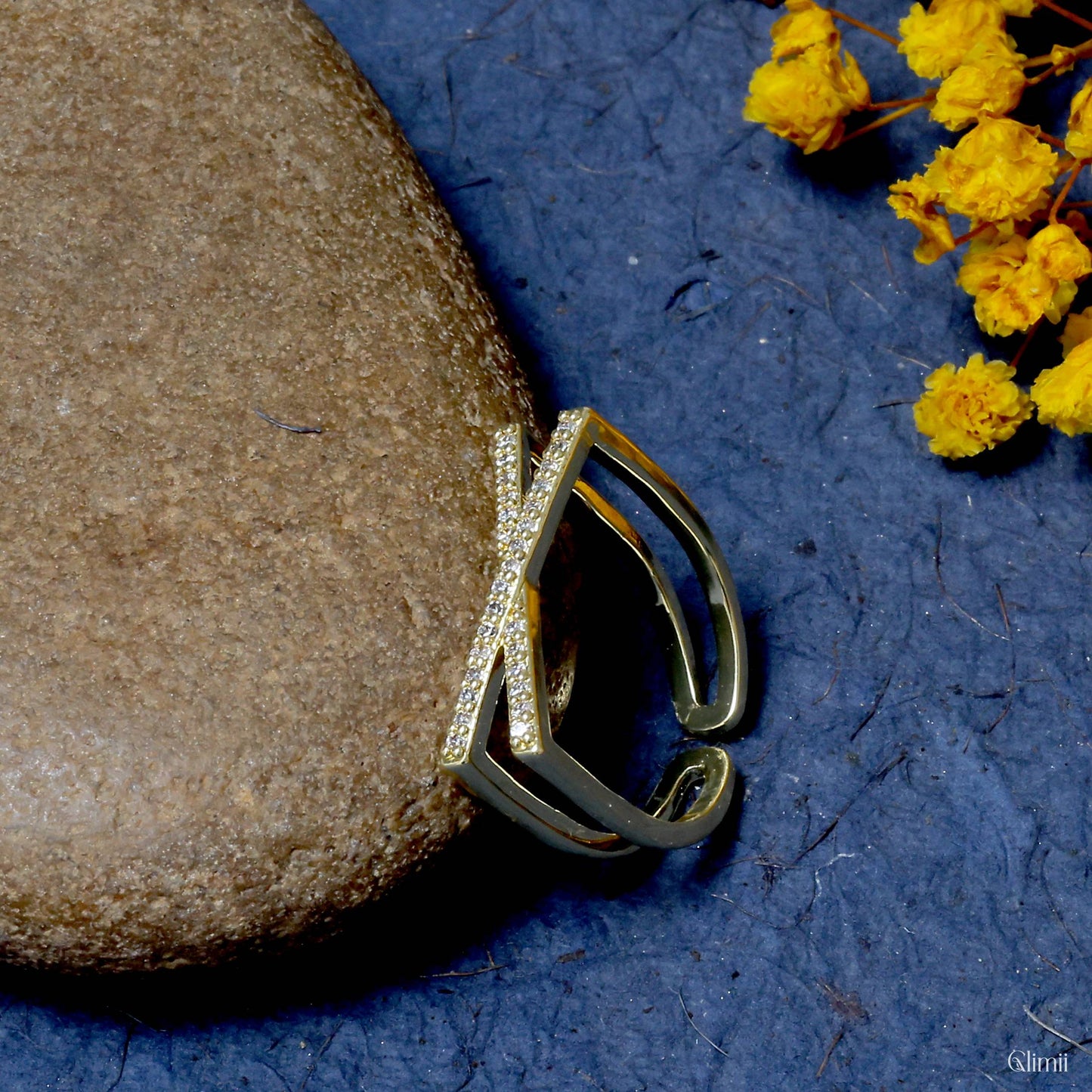 Glimii Korean style jewelry ring with intersecting design and small sparkling stones on blue background