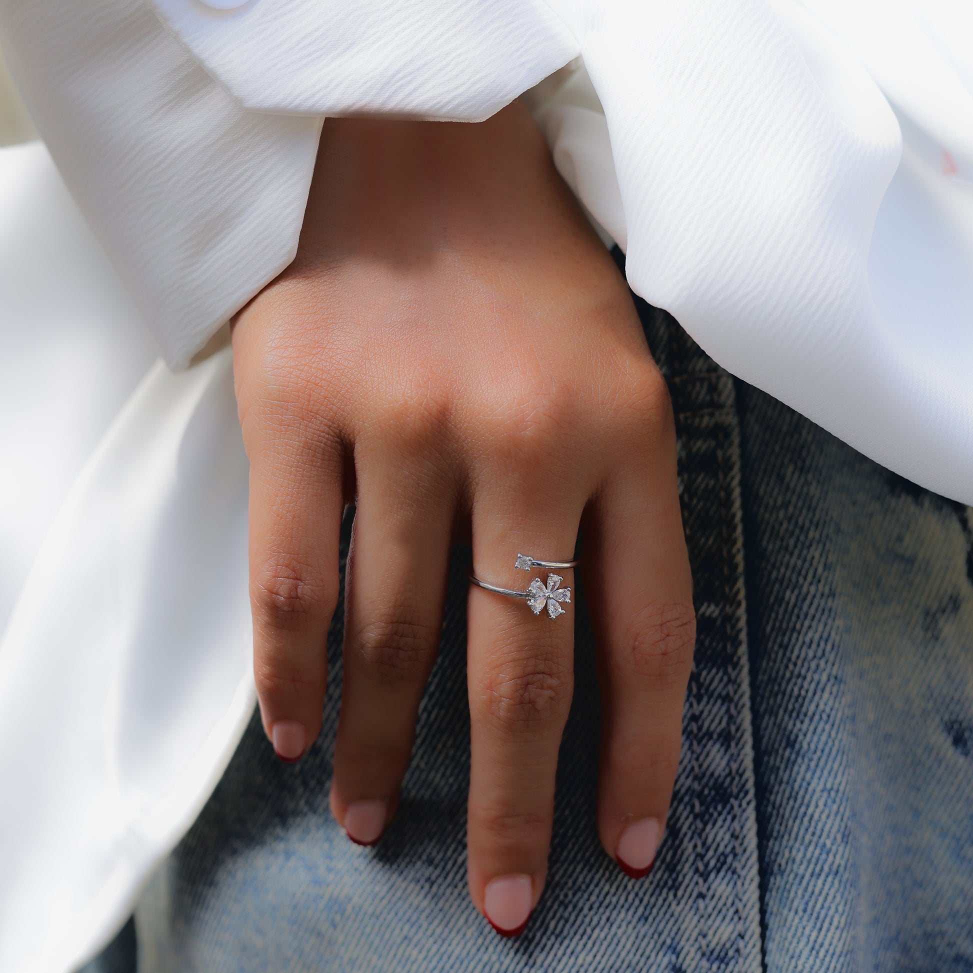 Glimii delicate flower jewelry for women featuring a silver floral ring on hand with white sleeve and denim