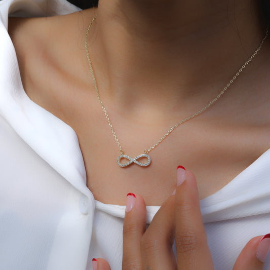 Glimii dainty infinity pendant necklace with delicate chain worn on a woman’s neck with white blouse