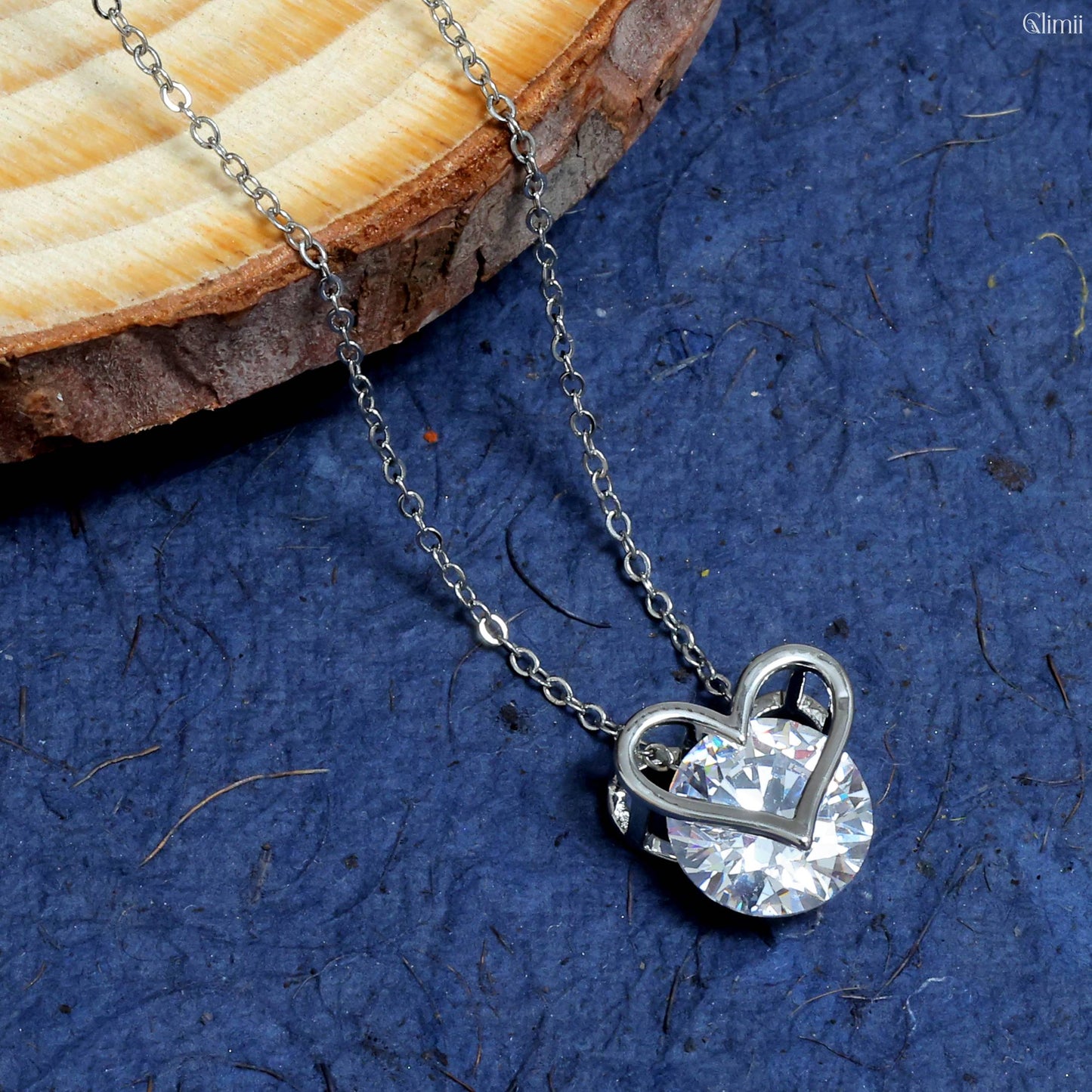 Glimii minimalist heart necklace with silver chain and crystal pendant on blue background