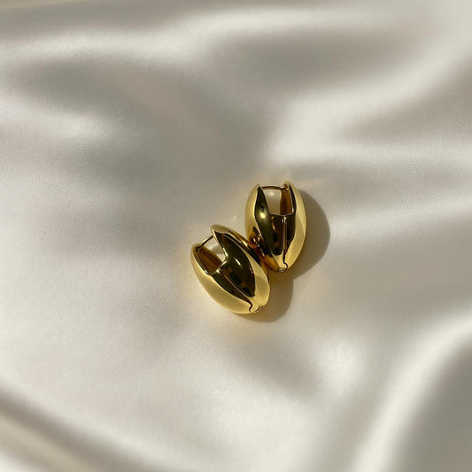 Glimii gold almond hoop earrings with smooth polished finish on white satin background
