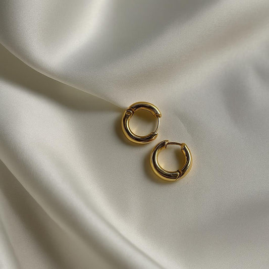 Glimii gold circle hoop earrings with smooth finish displayed on soft beige fabric background