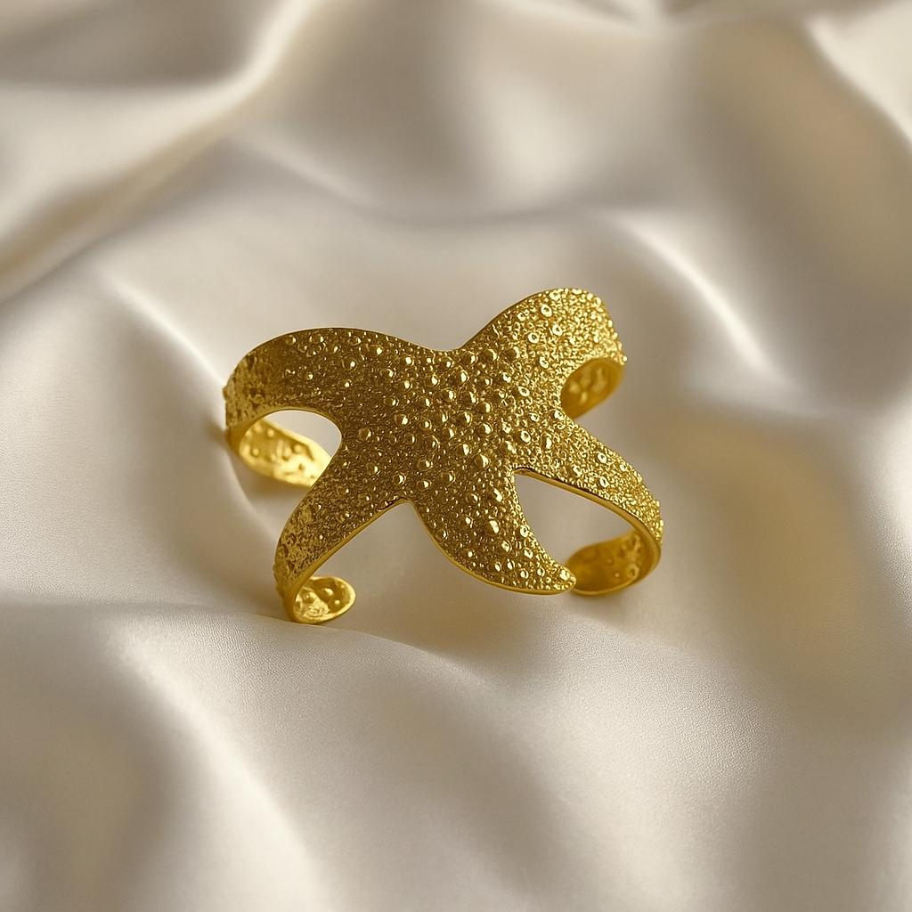 Glimii gold starfish ocean inspired jewelry cuff with textured surface on silk fabric