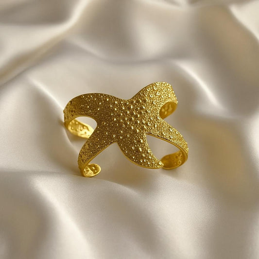 Glimii gold starfish ocean inspired jewelry cuff with textured surface on silk fabric