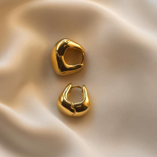 Glimii minimalist gold hoop earrings with smooth polished finish displayed on beige fabric