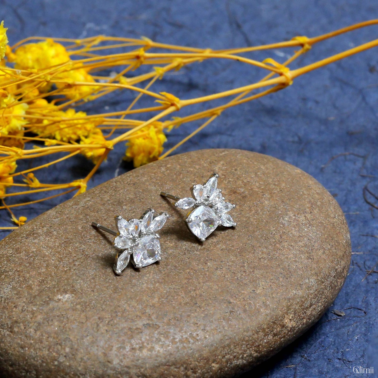 Glimii delicate everyday earrings with clear crystal stones arranged in a floral design on a stone