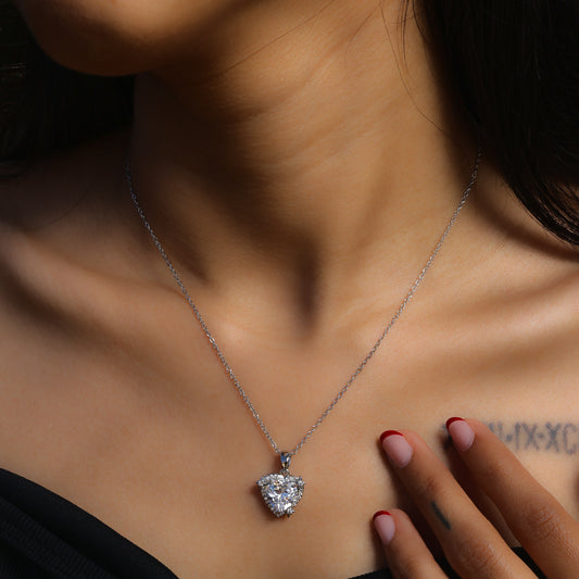 Glimii minimalist heart pendant necklace with a sparkling crystal on a silver chain worn on a woman’s neck