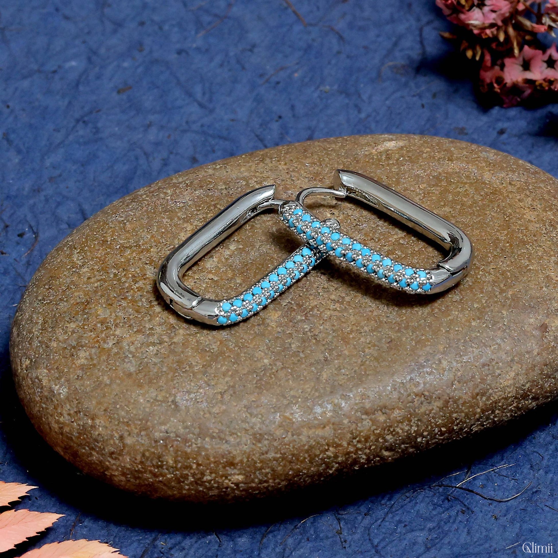 Glimii stainless steel minimalist earrings with blue stones on a smooth brown stone background