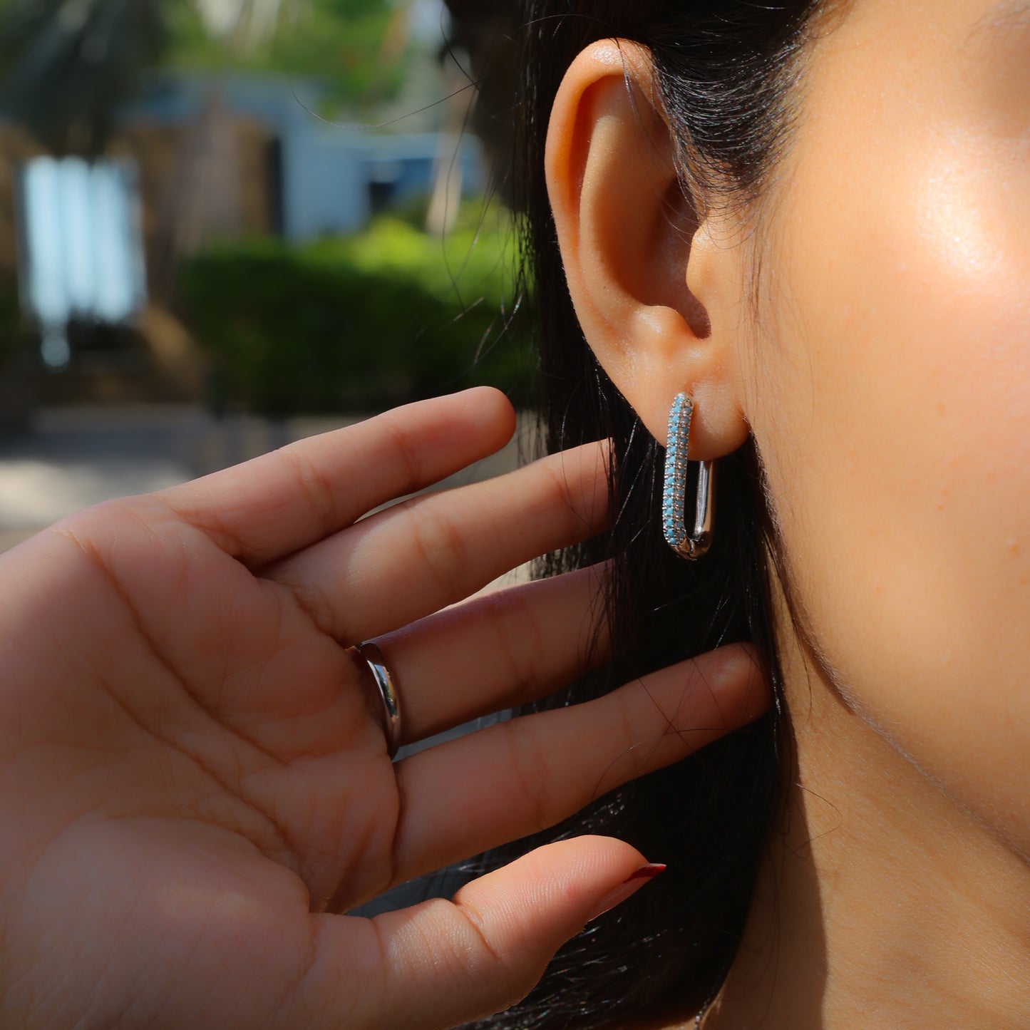 Glimii stainless steel minimalist earrings worn on ear with hand near face outdoors