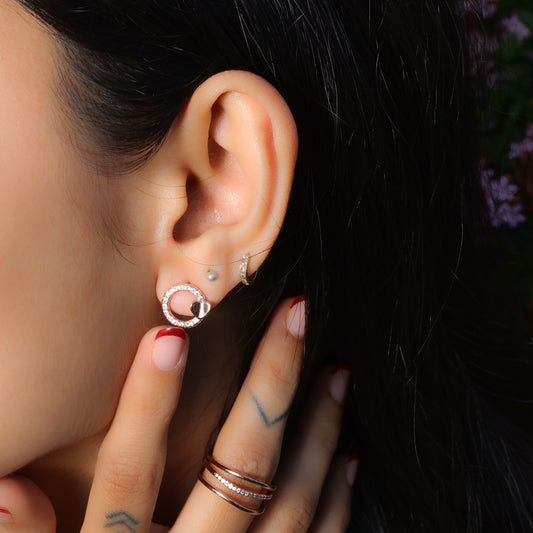 Glimii minimalist heart earrings worn on ear with additional small hoop and pearl studs